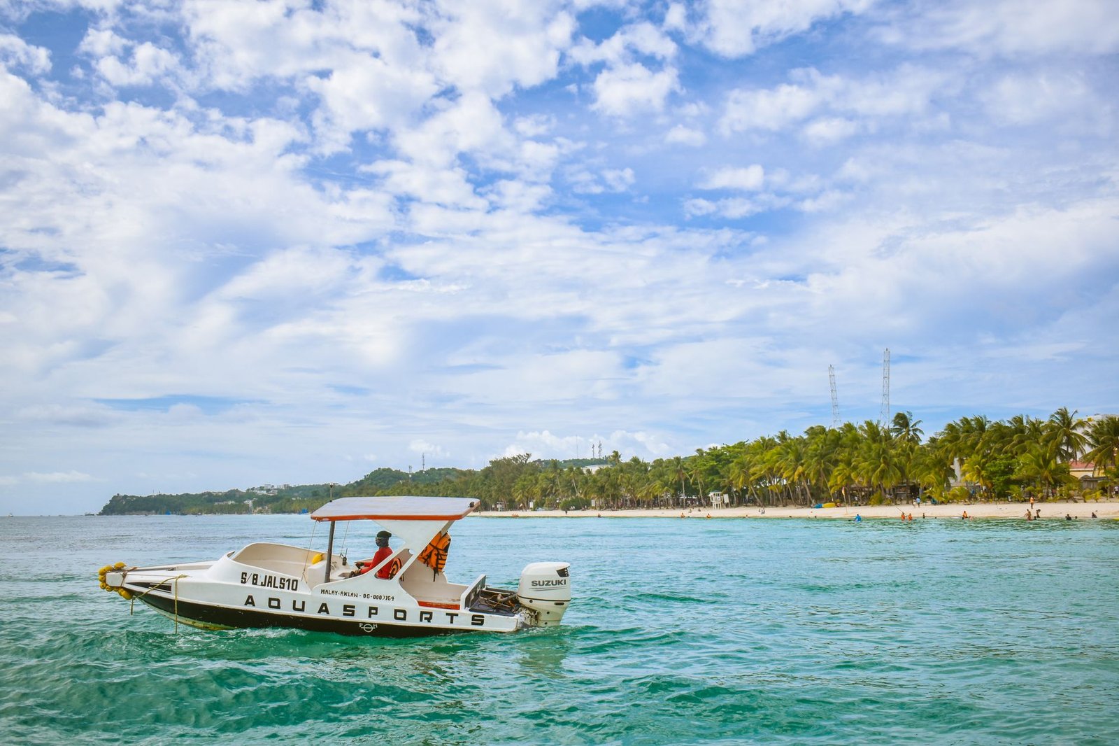 A bright summer scene showing a speedboat cruising near Boracay's white sand beach, Philippines