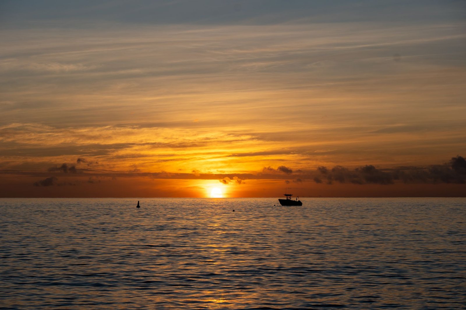 A peaceful sunrise over the ocean near Fiji's Kuata Island with a silhouette of a boat