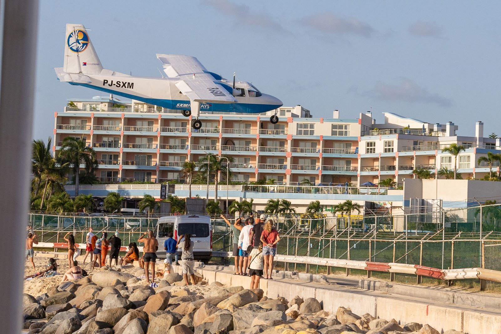 A plane flies low over tourists at Maho Beach, Sint Maarten, near the airport