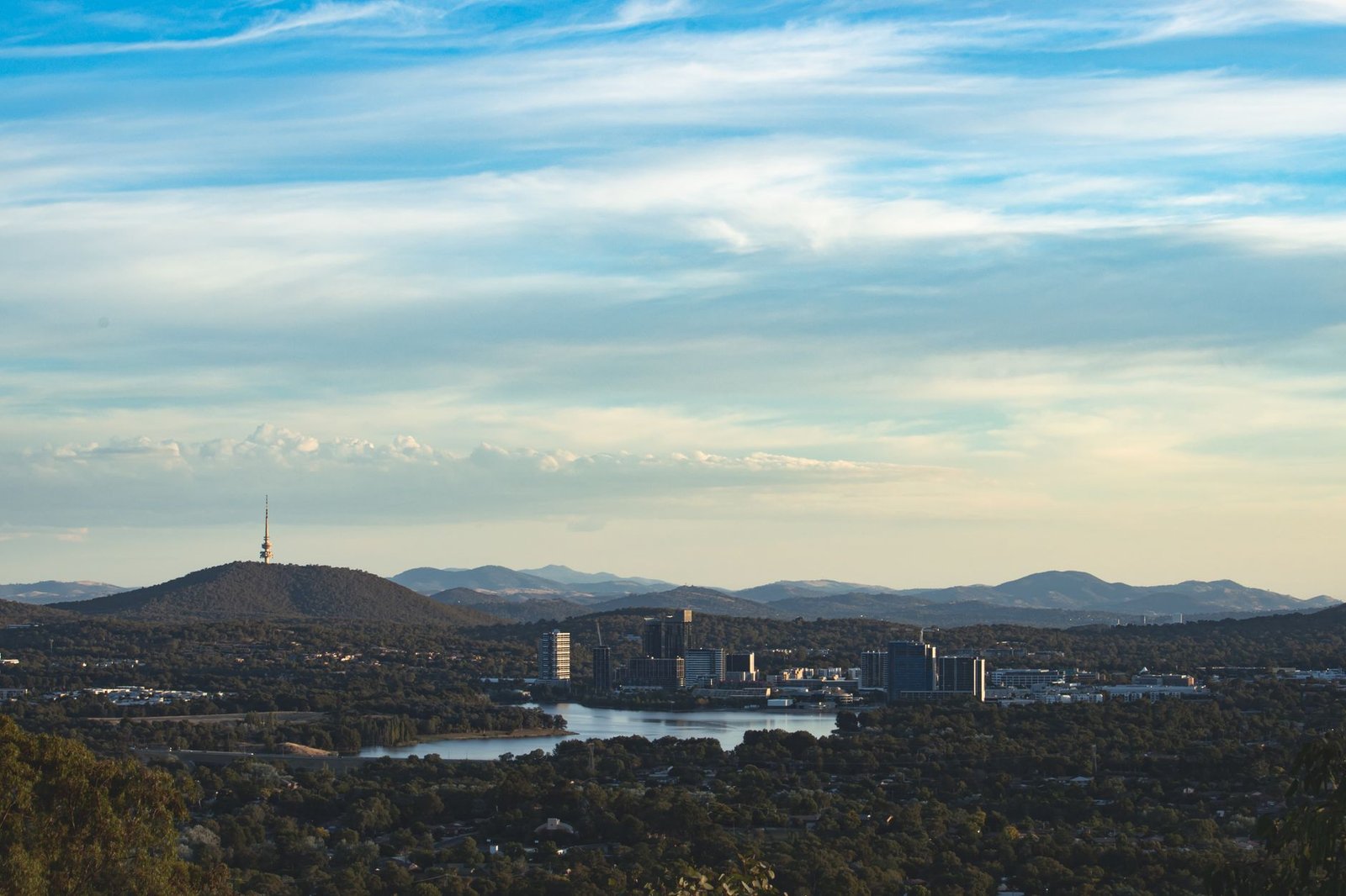A scenic aerial view of Canberra highlighting Telstra Tower and surrounding landscape under a blue sky
