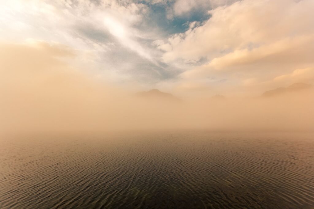 A serene fog-covered lake in the High Tatras, Slovakia, under a glowing sky