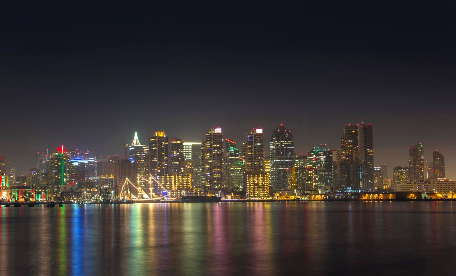 A serene night view of San Diego's illuminated skyline reflecting on calm water