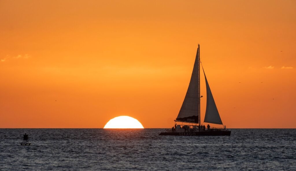 A small sailboat glides at sunset, providing an intimate view of the sky over Key West