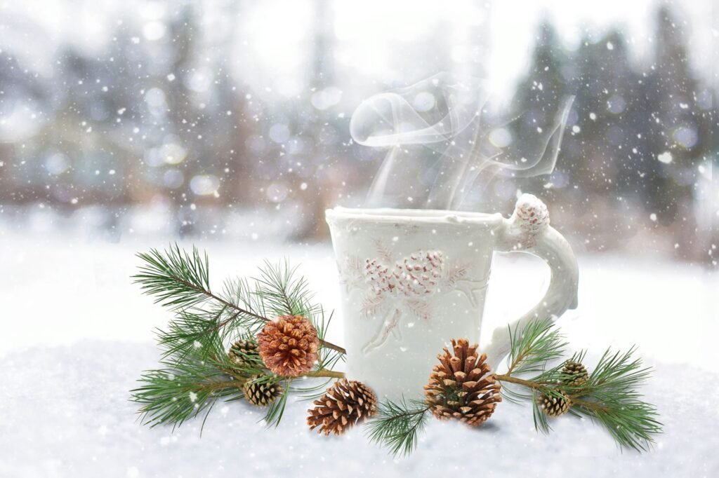 A steaming mug surrounded by pine branches and pinecones in a snowy winter landscape