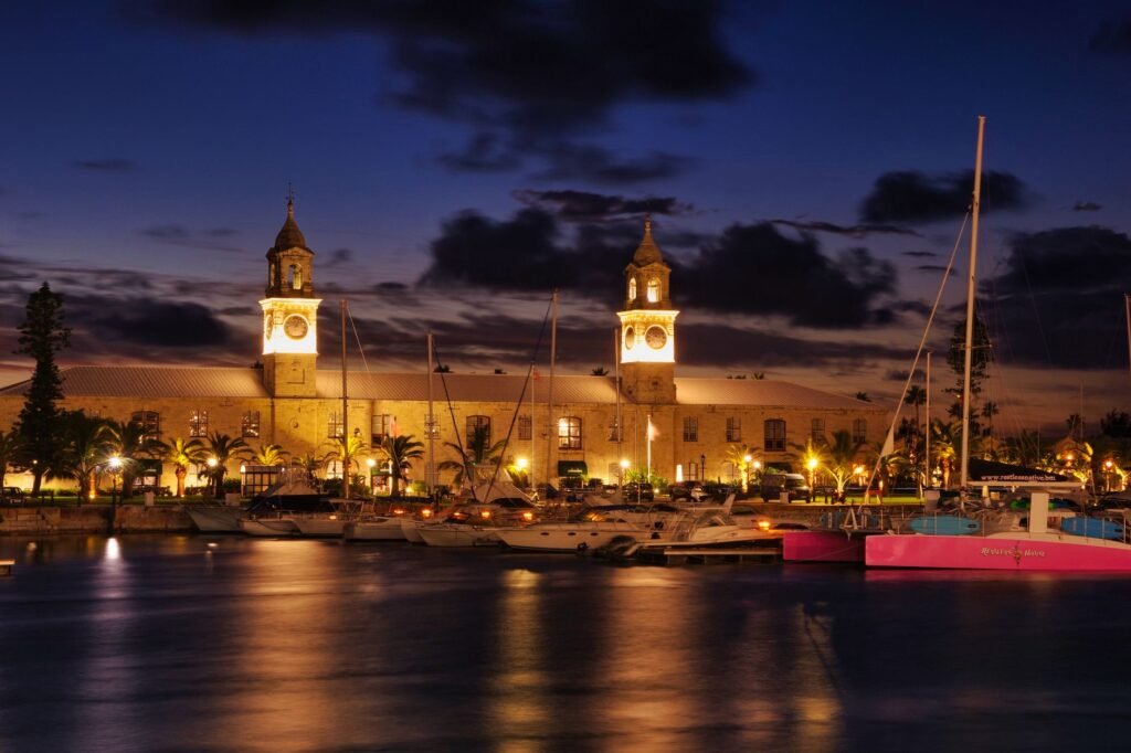 A stunning nighttime view of the Royal Navy Shipyard in Bermuda with illuminated clock towers and yachts