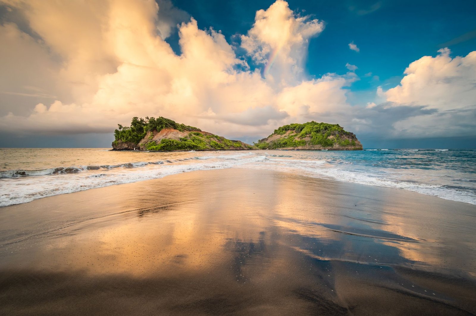 A stunning view of two lush islands off the coast of Sainte-Marie, captured at sunset with reflections on the sand