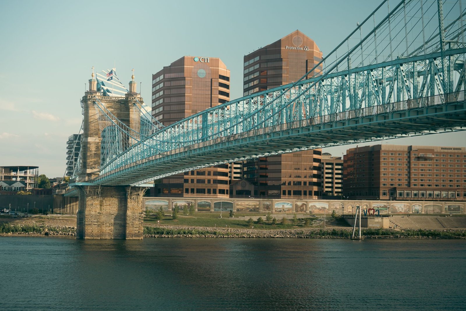 A view of Cincinnati's skyline featuring the iconic Roebling Suspension Bridge over the Ohio River at sunset