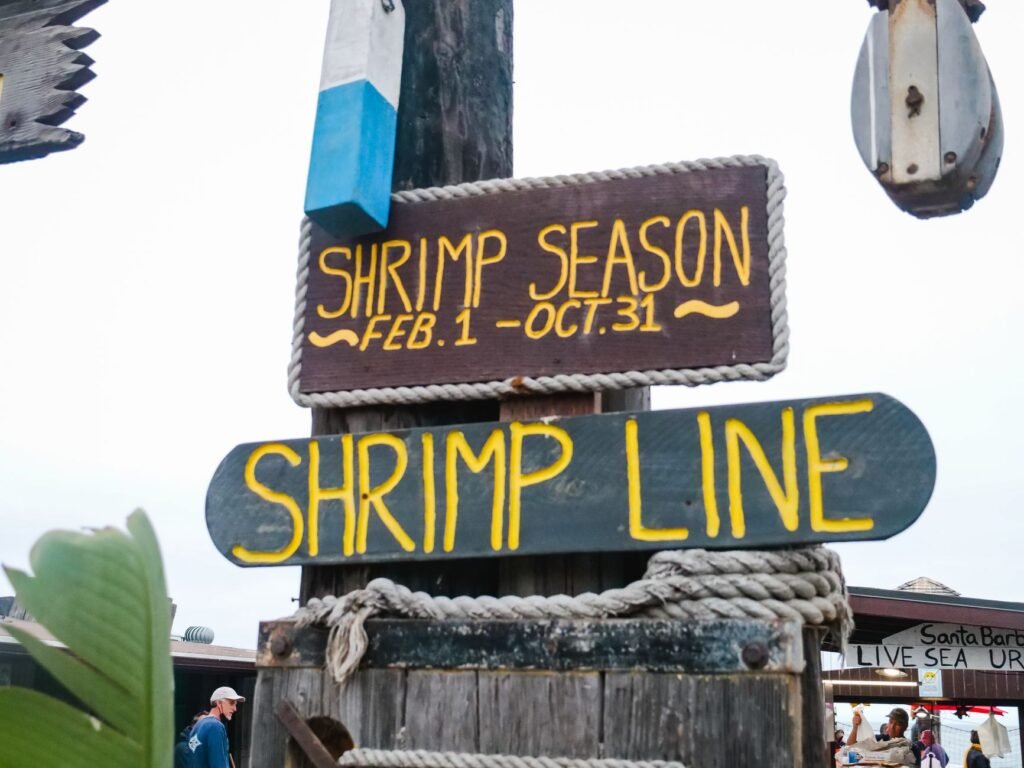 A wooden shrimp season sign at an outdoor market