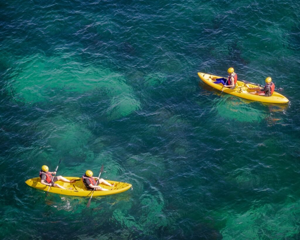 Aerial shot of people kayaking on clear turquoise water, enjoying a sunny day outdoors