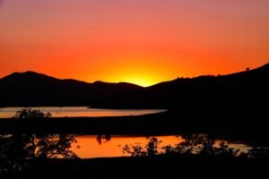 Capture the serene beauty of sunset over lake in Three Rivers, California, with silhouetted hills