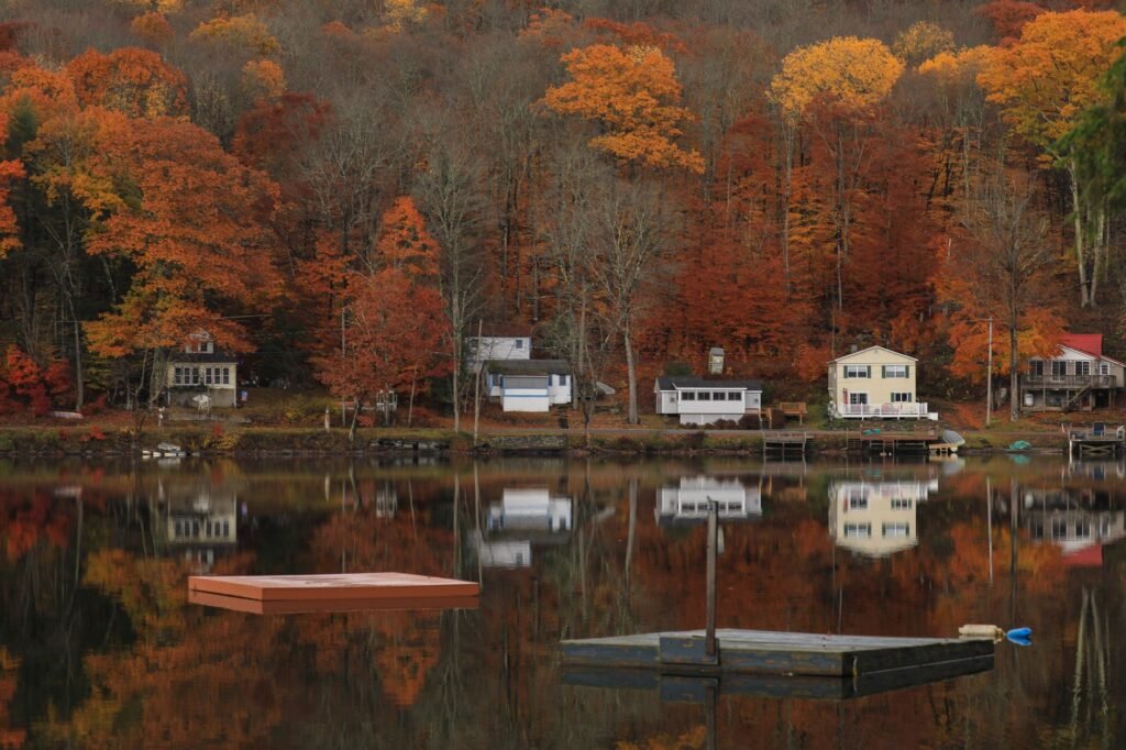 Charming autumn landscape with houses reflecting in a serene lake in Catskill, NY