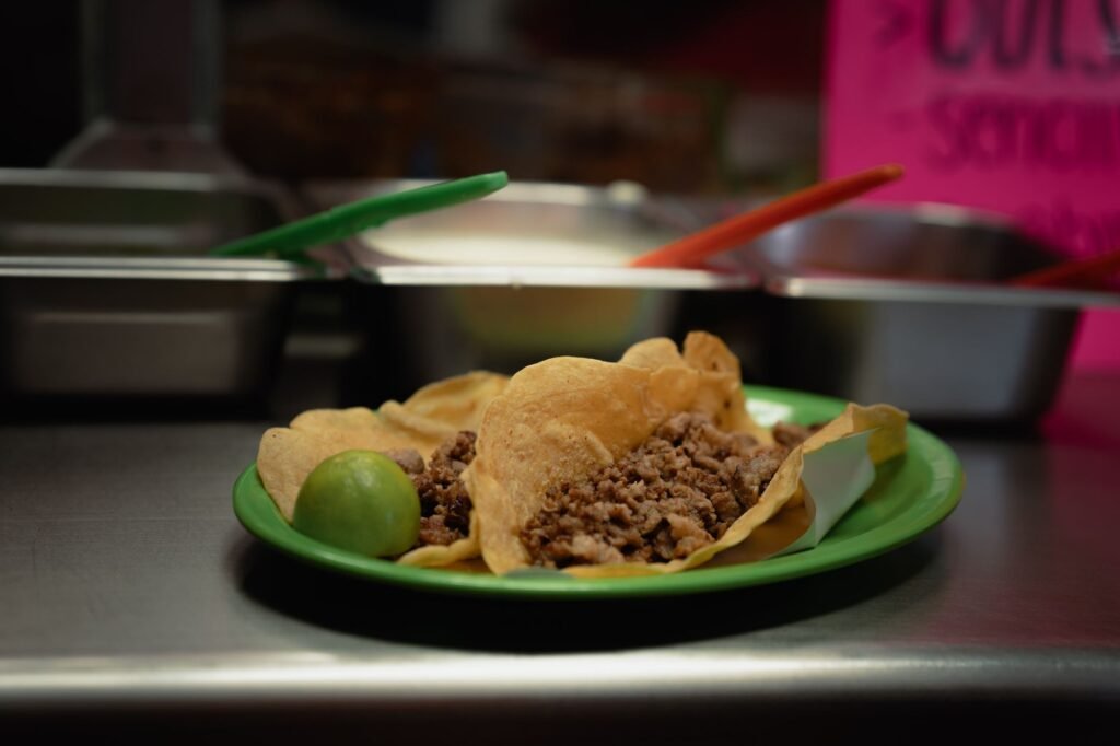 Close-up of delicious tacos with meat and lime, served on a green plate in a Mexican eatery