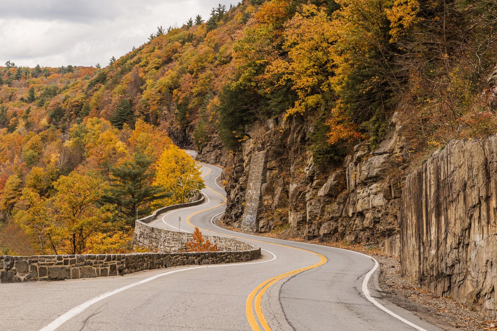 Curvy mountain road with vibrant fall foliage in New York's forested landscape