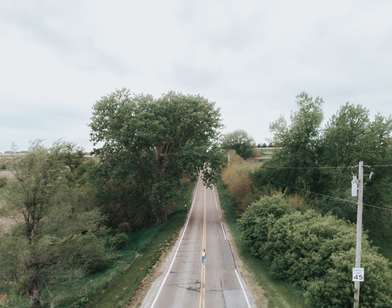 Drone image capturing a woman on a rural road surrounded by lush greenery in Omaha, Nebraska