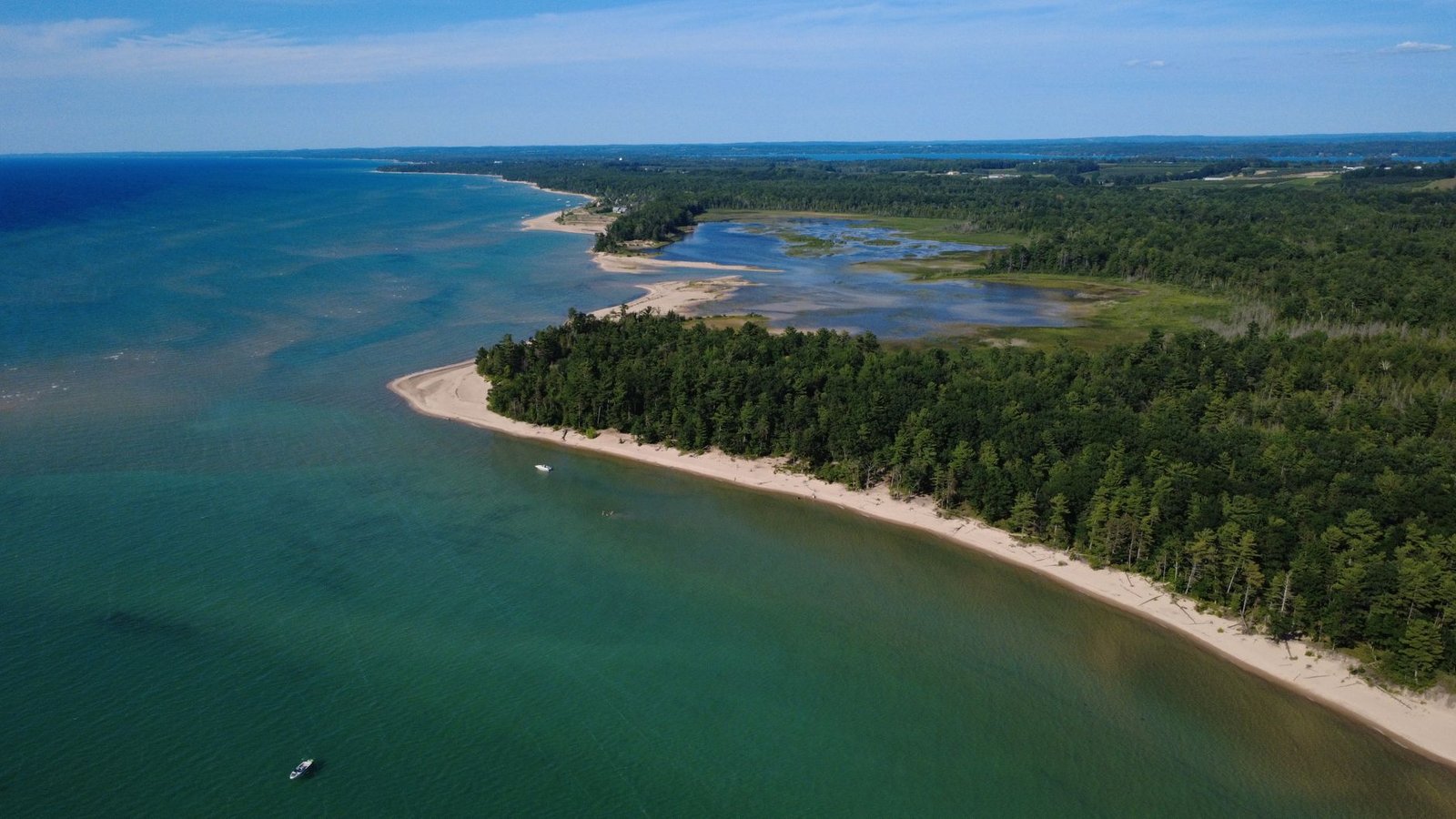 Drone shot of Michigan's coastal landscape with lush forests and clear waters in summer
