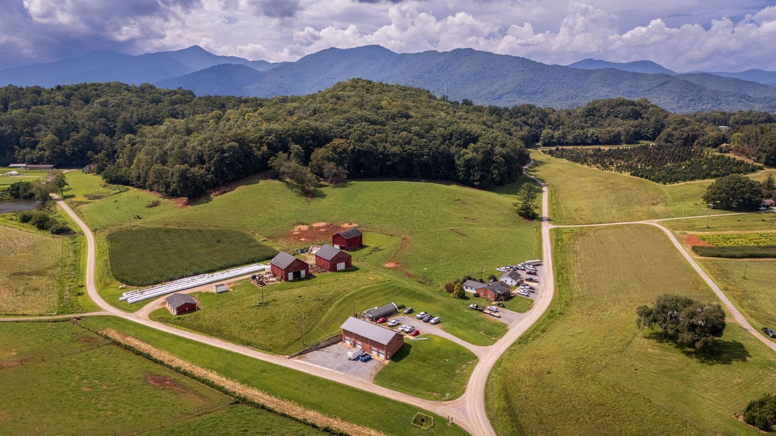 Drone view of a scenic farm landscape with distant mountains and lush greenery