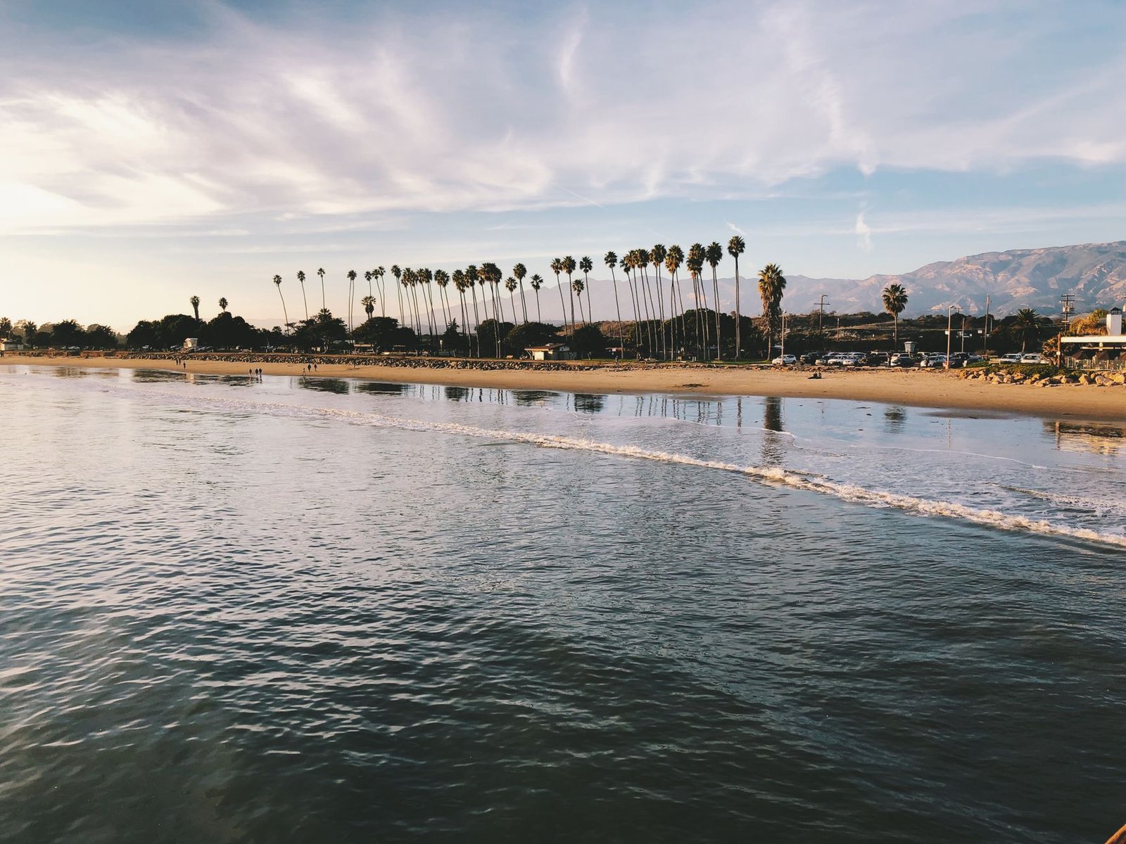 Stunning beach with palm trees and mountains at sunset