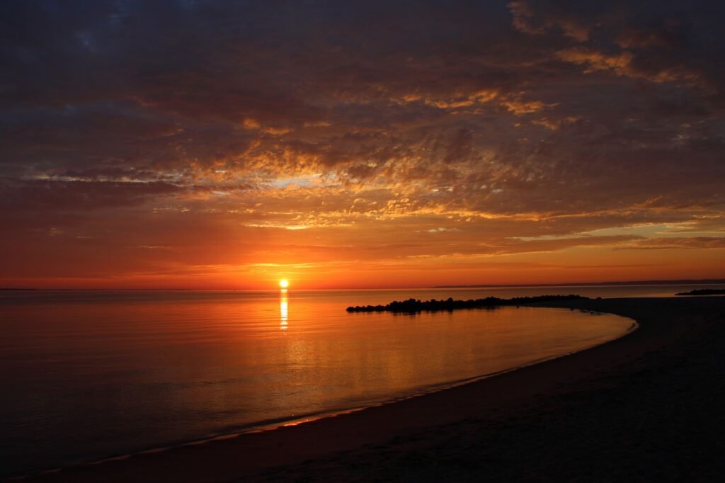 Sunrise over a sandy beach invites early‑morning swimmers and walkers